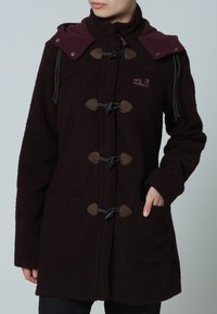 Burgunderfleecejacka med hög krage, knäppningar med togglar och två framfickor. Accenterad med en kontrasterande mörkröd huva.