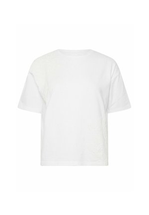 Camiseta blanca de manga corta con cuello redondo y una sutil bordado floral texturizado en el hombro superior izquierdo y en el lado inferior derecho.