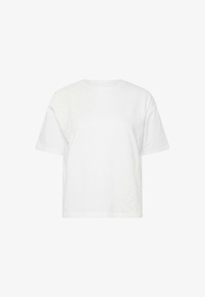 Camiseta blanca de manga corta con cuello redondo y una sutil bordado floral texturizado en el hombro superior izquierdo y en el lado inferior derecho.