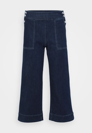 Dark blue denim wide-leg pants feature a high waist, two front pockets, and three button accents on the waistband.