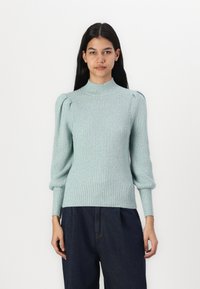 Light blue ribbed sweater with a high neck and puffed sleeves, featuring a soft texture and fitted bodice. Worn with dark denim pants.