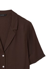Camicia marrone a maniche corte con colletto a scollo, realizzata in un tessuto leggero e testurizzato, con bottoni bianchi nella parte anteriore.