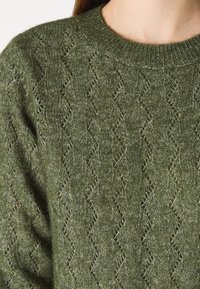 Maglione verde lavorato a maglia con motivo a diamante testurizzato e colletto rotondo a costine, realizzato in un tessuto morbido e caldo.