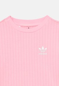 Ροζ ριμπ T-shirt της Adidas με στρογγυλή λαιμόκοψη και λευκό λογότυπο στο  στήθος. Απαλή υφή υφάσματος και κομψός σχεδιασμός.
