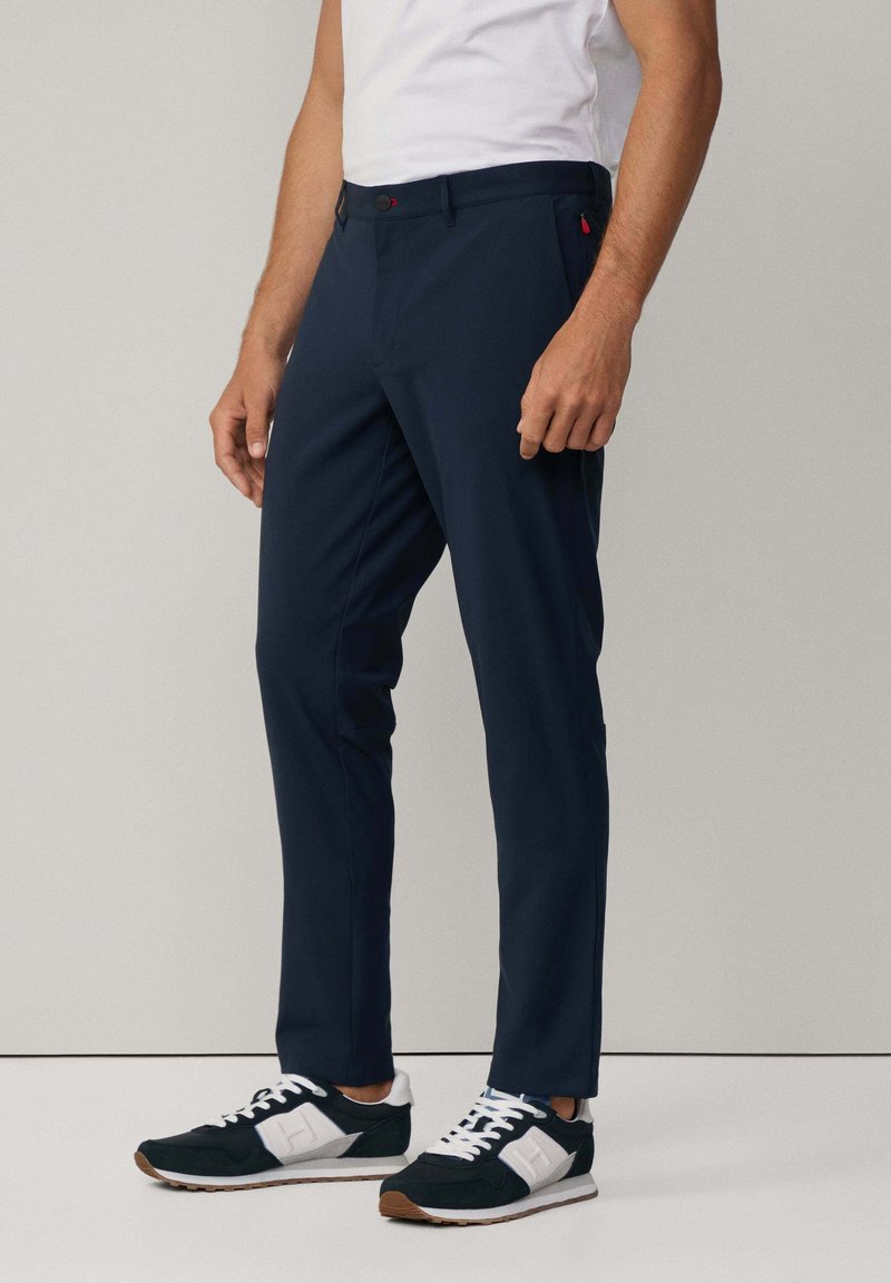 Pantaloni blu navy realizzati in tessuto leggero, con vestibilità slim, tasche laterali discrete e dettagli con bottoni rossi in contrasto.