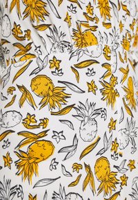 Tissu blanc avec un motif ananas et feuilles tropicales en jaune et noir, présentant de petites fleurs et des motifs de feuilles dispersés.