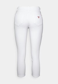 Vita högmidjade skinny jeans med två bakfickor, kort längd och en liten triangulär röd logga på den högra fickan.