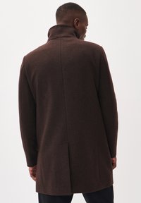 Bruine wollen jas met een hoge kraag, getailleerde pasvorm en lange mouwen, voorzien van een achterventiel voor bewegingsvrijheid.