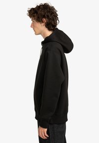 Black hooded sweatshirt with long sleeves, made of soft fabric. Features a kangaroo pocket and ribbed cuffs and hem. Simple design.