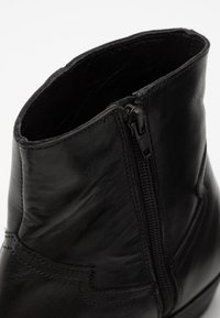 Schwarze Leder-Ankle Boots mit seitlichem Reißverschluss, glatter Textur, runder Zehenpartie und subtilen Nähten entlang der Kanten.
