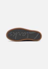 Rubber shoe sole with a gray textured surface and a brown, raised ridged edge. Features a prominent logo in the center.
