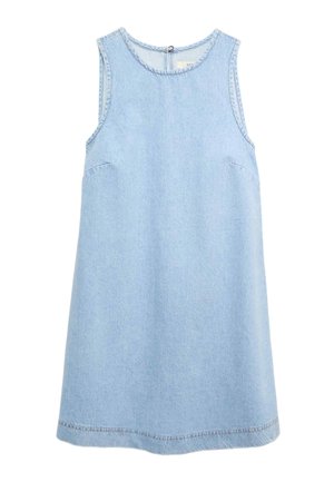 Kvinde iført en ærmeløs, lyseblå denim A-formet kjole, stående sideværts mod en ensfarvet baggrund.