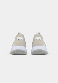 Pair of beige and white athletic sneakers shown from the back with textured white soles and small colored tabs near the heel.
