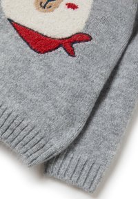 Pull en maille gris avec une finition texturée, arborant un motif brodé crème et rouge ressemblant à un visage et un foulard rouge.