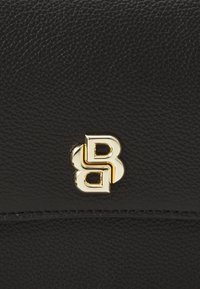 Portafoglio in pelle nera texture con un logo in metallo dorato ben visibile, caratterizzato da lettere intrecciate. Design elegante con dettagli di cucitura discreti.