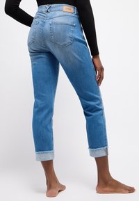Blaue Jeans aus Denim mit lässiger Passform, umgeschlagenen Säumen, Fünf-Taschen-Design und einem Lederlogo-Patch am hinteren Bund.