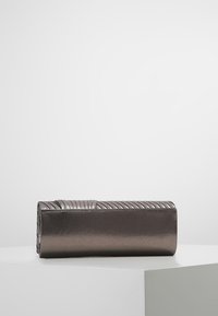 Metallisk kuvertväska med rektangulär form, med en ribbad textur på toppen och en slät yta. Färgen övergår från mörka till ljusare metalliska nyanser.