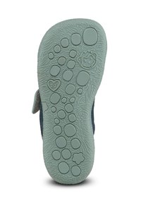 Semelle d’une chaussure d’enfant avec des empreintes de pattes texturées, un singe souriant, un cœur avec la taille 21, et des formes abstraites pour l’adhérence.