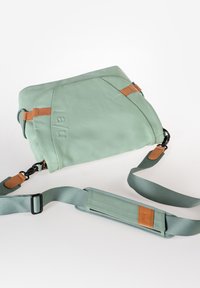 Grüne Leder-Crossbody-Tasche mit braunen Akzenten, rechteckiger Form, verstellbarem Riemen und geprägtem Logo auf der Vorderseite. Glatte Textur.