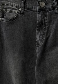 Jeans de mezclilla negra con una textura suave, que cuentan con un cierre de botón y un diseño de cinco bolsillos. Incluyen costuras sutiles y un corte clásico.