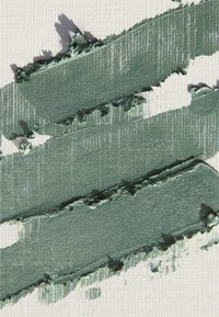 Tre tykke, ujevne horisontale striper med strukturert metallisk grønn maling på en hvit ribbet overflate.