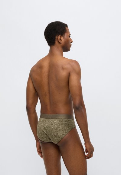 Khaki majtki w wzory z teksturowanej tkaniny, z jednolitym pasem w talii. Tło jest jasne i gładkie, podkreślając wzór.