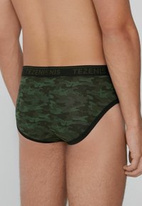 Grüne Camouflage-Herrenbriefs mit einem schwarzen elastischen Taillengummi und "TEZENIS"-Logo, körperbetontem Design und weichem Stoff. 