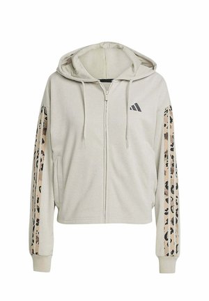 Sudadera beige cropped de tejido suave con cremallera en el frente, con rayas de estampado de leopardo en las mangas y un logo de Adidas en el pecho.