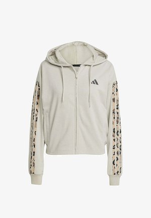 Sudadera beige cropped de tejido suave con cremallera en el frente, con rayas de estampado de leopardo en las mangas y un logo de Adidas en el pecho.