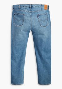 Jeans de denim azul claro con corte recto, cinco bolsillos y una etiqueta de marca de cuero marrón en la parte trasera. Textura desgastada en la tela.