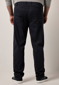 Pantalones azul marino oscuros con un diseño de pierna recta, dos bolsillos traseros y una textura de tela suave, combinados con zapatillas oscuras de corte bajo.