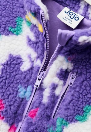 Violetti fleece-takki, jossa on pörröinen rakenne, värikkäitä kuvioita vaaleanpunaisena, vihreänä ja valkoisena sekä vetoketjullinen etuosa, jossa on lilac-väriset yksityiskohdat.