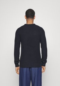 Navy knitted sweater with textured fabric, round neckline, and long sleeves. Ribbed cuffs and hem, fitted silhouette.