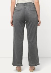 Pantalones acampanados grises de mezclilla, con cintura alta, dos bolsillos traseros y una textura suave, con un dobladillo limpio y sin patrones visibles.