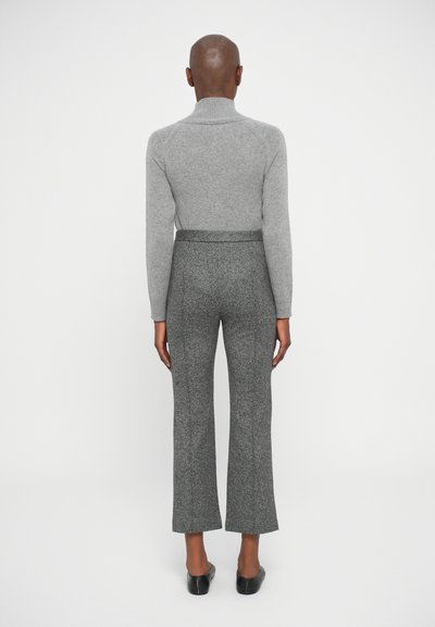 Pull à col roulé gris, ajusté, en texture côtelée. Pantalons gris à motifs, évasés, taille mi-haute, en tissu doux. Des chaussures noires à enfiler complètent la tenue.