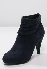 Granatowe zamszowe botki za kostkę z zagiętym kołnierzem i 10-centymetrowym obcasem. Gładka tekstura i ostro zakończony nosek.