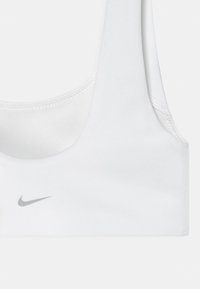 Λευκό αθλητικό σουτιέν Nike με λεπτές τιράντες και μικρό γκρι λογότυπο Nike στο κέντρο μπροστά.