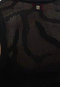 Μαύρο ύφασμα με δίχτυ και αφηρημένο πλεκτό σχέδιο, με μικρό χρυσό μεταλλικό λογότυπο "HUGO" κοντά στο επάνω κέντρο.