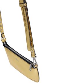 Złota metaliczna torebka crossbody z czarną podstawą, z zamknięciem na zamek i ozdobnymi srebrnymi akcentami na pasku. Logo wytłoczone na przodzie.