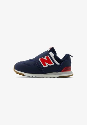 Marineblauwe sneaker met rode en witte accenten, klittenbandsluiting, gestructureerde stof, rubberen zool en een opvallend "N"-logo aan de zijkant.
