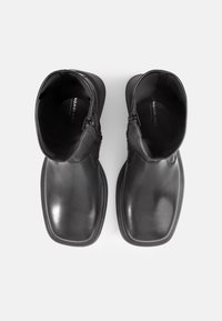 Bottines en cuir noir avec une finition lisse, bout carré et fermeture éclair sur le côté extérieur. L'intérieur est doté d'une semelle rembourrée.