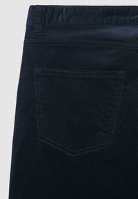 Dunkelblaue Cordhosen mit einer strukturierten Oberfläche, die eine einzelne Gesäßtasche mit verstärktem Nähedetail aufweisen.