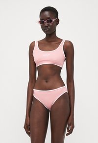 Rosa bikini-set med en cropped topp og høy midje-bukse med hvite detaljer. Teksturert stoff, minimalistisk design, ingen mønstre.