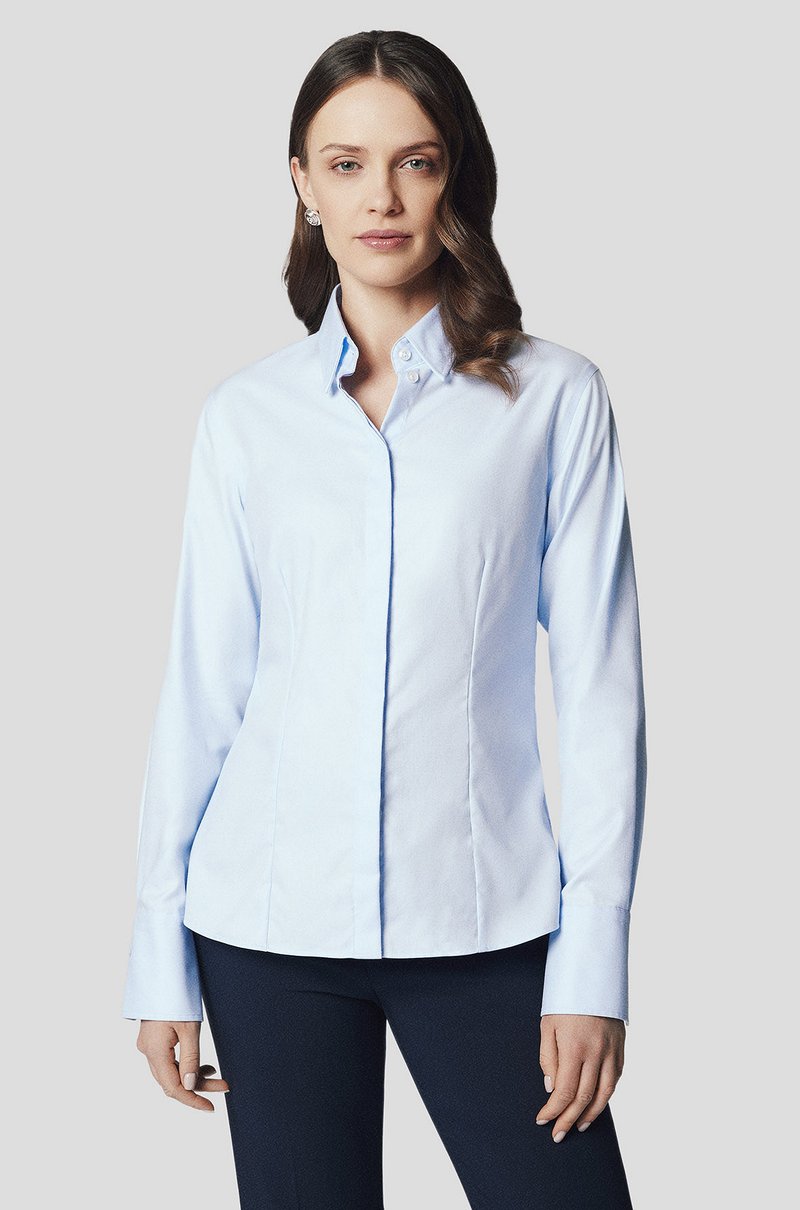 Jasnoniebieska koszula zapinana na guziki o strukturalnym kroju, długich rękawach i spiczastym kołnierzu, z wąskim fasonem i subtelnymi detalami przeszyć.