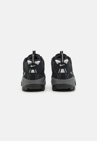 Black athletic shoes with a textured finish, featuring a padded collar, white accents, and a black and white patterned sole.