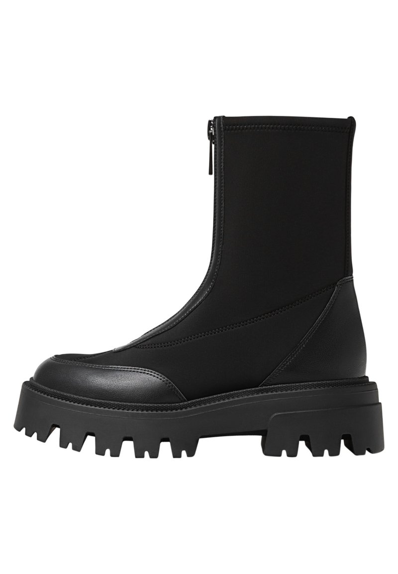 Bottines noires à fermeture éclair, avec un embout en cuir lisse et un design montante texturé. Semelle épaisse en caoutchouc robuste.