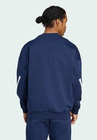 Marineblauwe sweatshirt met lange mouwen, ribbelmanchetten en onderrand. Bevat witte accenten op de mouwen. Zachte textuur en ontspannen pasvorm.