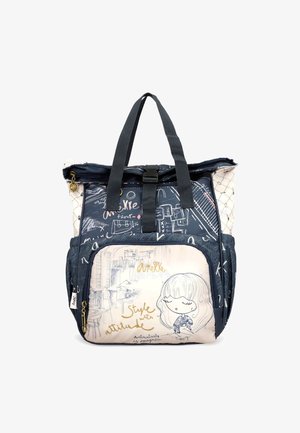 Sac à dos bleu marine et beige clair avec un tissu texturé, présentant une illustration graphique et des accents de texte dorés. Il possède des poignées supérieures et une poche zippée.