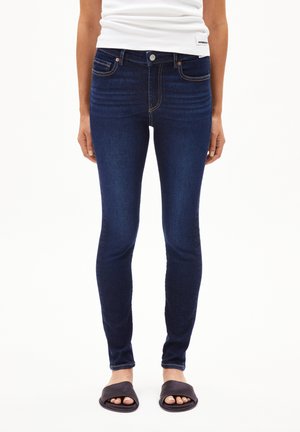 Schmale Jeans aus dunkelblauem Denim mit klassischem Fünf-Taschen-Design, dezenten Steppdetails und einer glatten, dehnbaren Textur.