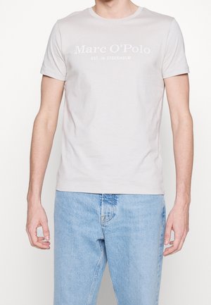 Jasnoszara bawełniana koszulka z okrągłym dekoltem, krótkimi rękawami i nadrukiem z przodu z napisem "Marc O'Polo EST. W Sztokholmie". Casualowy krój.